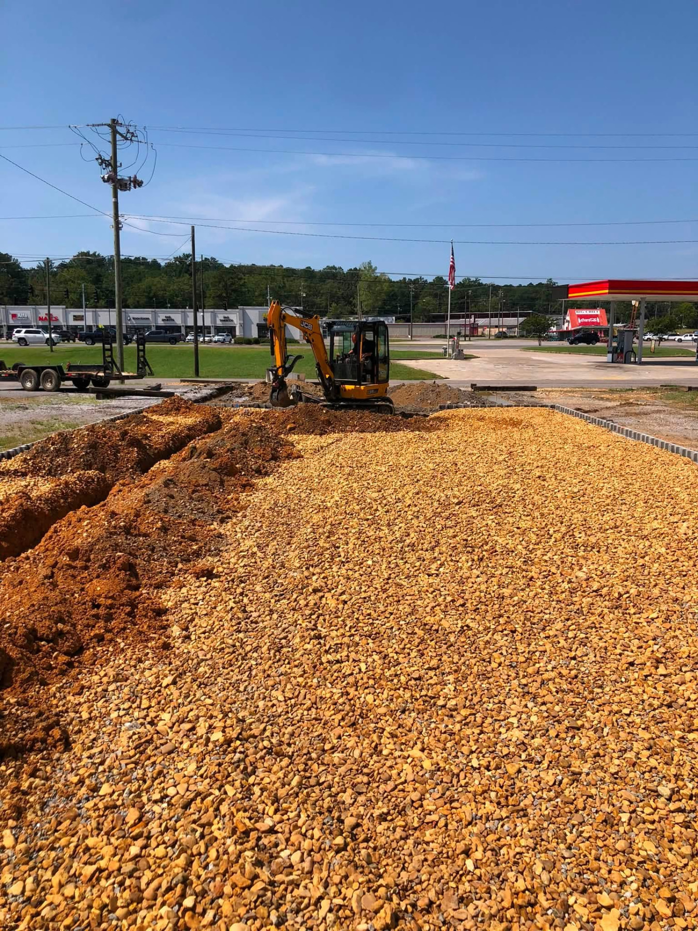 Mini-excavator trenching a new water and sewer line beside a commercial lot in Gadsden, Alabama